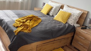 Un lit bien fait, recouvert d’une couette grise, de deux oreillers jaunes et d’un plaid jaune.