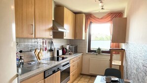 Une cuisine dotée de meubles en bois, d’un four à micro-ondes, d’une cuisinière et d’une table à manger, cette dernière étant mise avec des assiettes et des tasses.