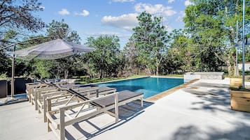 Relax by the pool surrounded by lush greenery and enjoy a comfortable patio area.