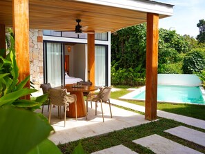 A modern outdoor dining area with a table and chairs, a pool, and lush greenery. - Villa Palmira - 2 bedroom Bali style Pool Villa (Bo Phut)