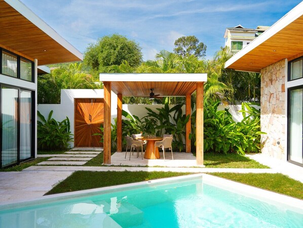 A modern house with a swimming pool, a covered outdoor dining area, and lush greenery. - Villa Palmira - 2 bedroom Bali style Pool Villa (Bo Phut)