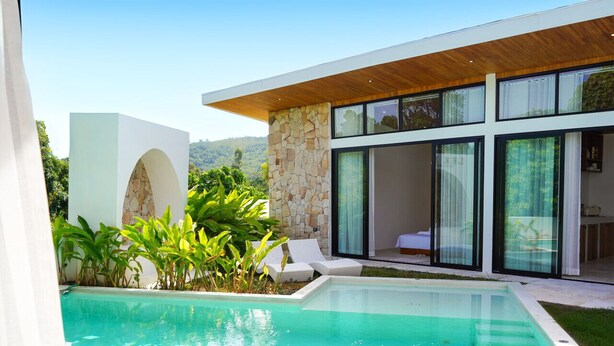 A modern house with a swimming pool, white exterior walls, and a stone facade.