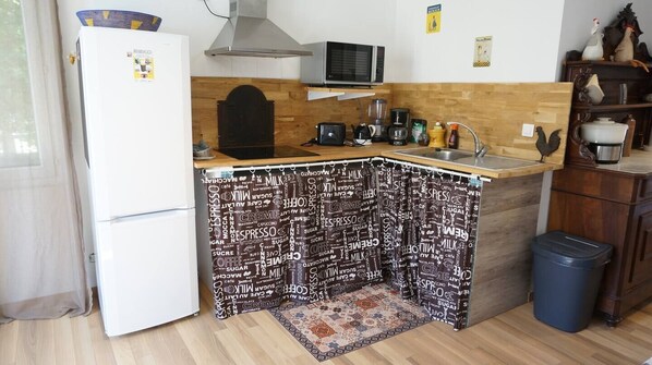 Une cuisine compacte équipée d’un réfrigérateur, d’un four à micro-ondes, d’un grille-pain, d’un évier et d’une machine à café.