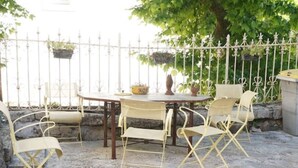 An outdoor patio with a stone floor, a round table, and four yellow chairs. - Apartment n°3 - T2 bedroom & separate bathroom (Lamalou-les-Bains)