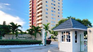 Una entrada protegida por una reja a Turtle Beach Towers, con un pequeño quiosco y un área pavimentada que incluye un desagüe.