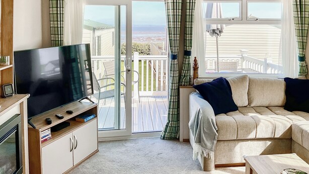 Ein gemütliches Wohnzimmer mit Flachbildfernseher, einer Couch und einem Balkon mit Blick.