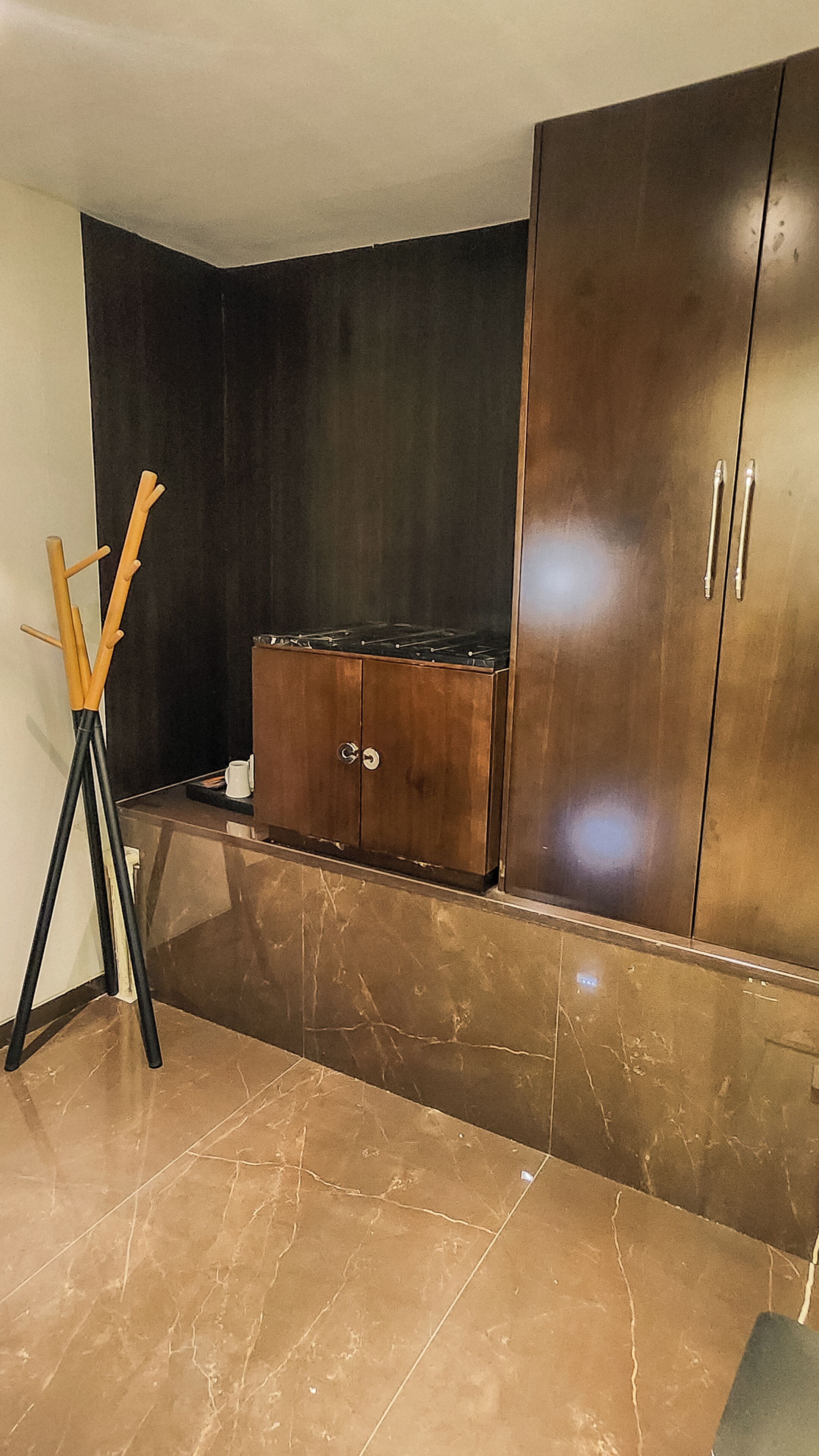 A room with a dark wall, a wooden cabinet, and a tripod.