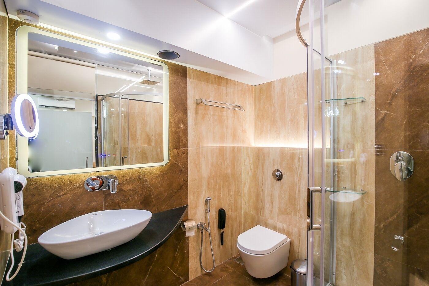 Ein modernes Badezimmer mit großem Spiegel, Waschbecken, Toilette und einer Duschkabine.