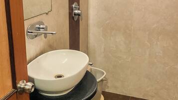 A bathroom with a white sink, a shower head, and a toilet.