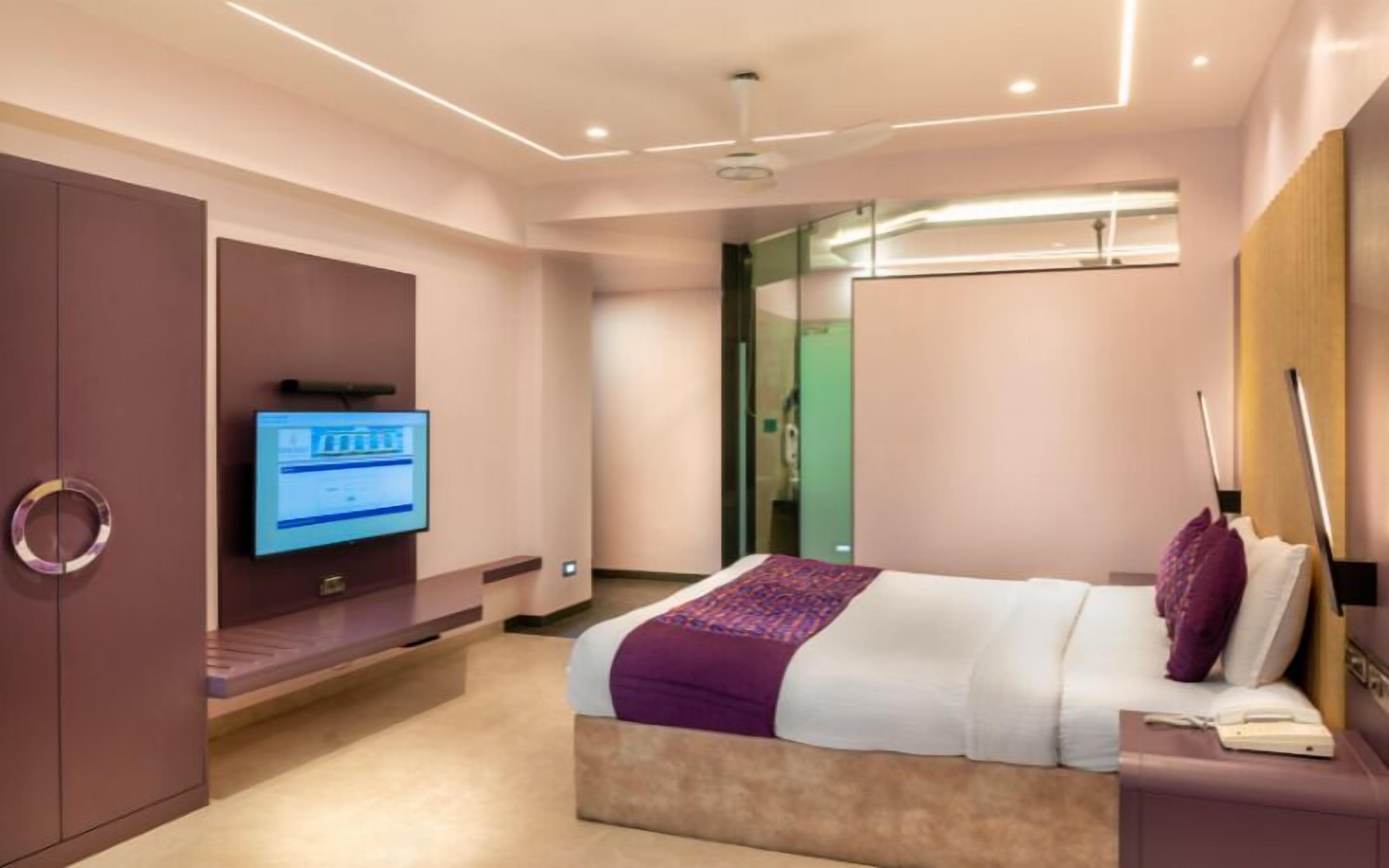 A modern hotel room with a bed, a television, and a desk.