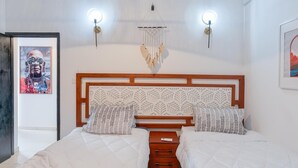 Una cama doble con cabecera de madera, dos mesitas de noche y lámparas fijadas a la pared.