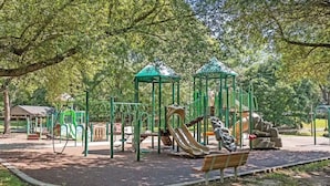 Un parque infantil con toboganes y estructuras para escalar, rodeado de árboles.