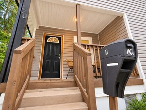A wooden staircase leading to a front door with a mailbox.