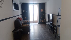 A living room with a sofa, a TV on a stand, and a bookshelf. - Apartment downtown Forcalquier (Forcalquier)