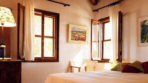 A bedroom with a wooden bed, a ceiling fan, and a window with curtains. - Cozy 1-bedroom apartment overlooking the Ionian sea. (Tragana)