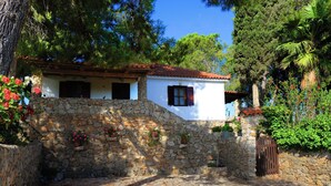 A stone-walled building with a tiled roof, a wooden gate, and potted plants. - Cozy 1-bedroom apartment overlooking the Ionian sea. (Tragana)