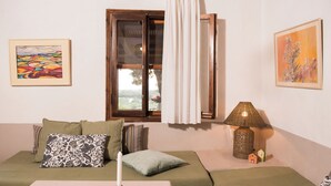 A room with a sofa, a table with a candle, a lamp, and two paintings on the wall. - Cozy 1-bedroom apartment overlooking the Ionian sea. (Tragana)
