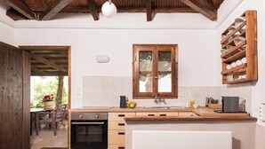 A kitchen with wooden cabinets, a built-in oven, a sink, and a window above it. - Cozy 1-bedroom apartment overlooking the Ionian sea. (Tragana)