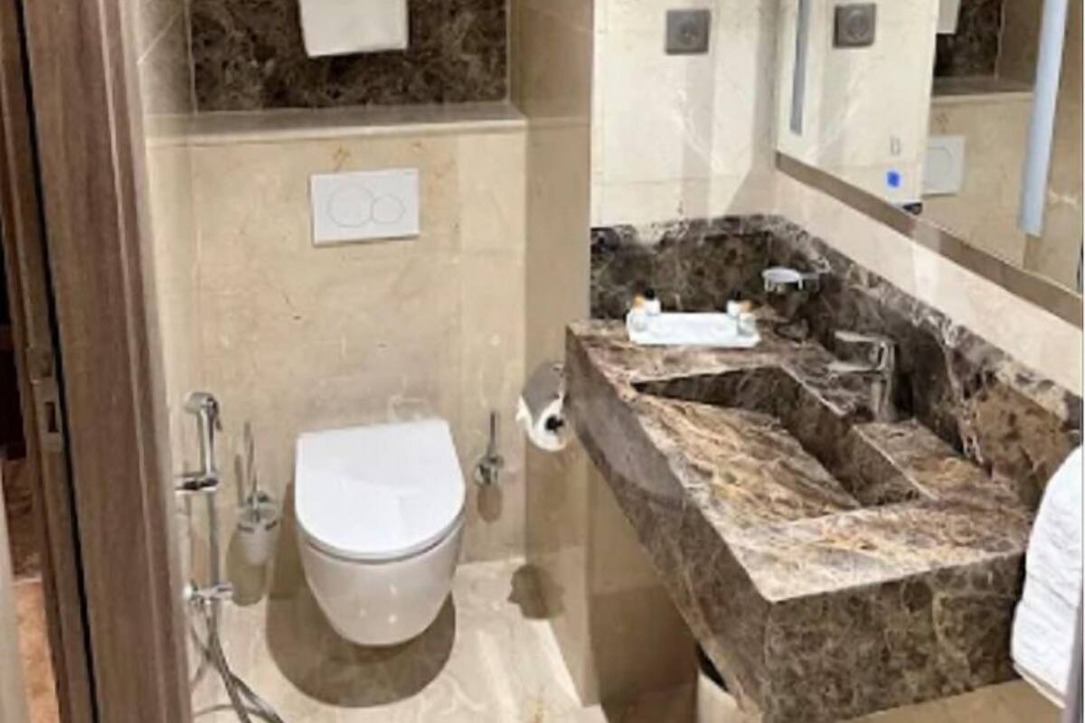 A bathroom with a marble vanity, a toilet, a sink, and a shower.