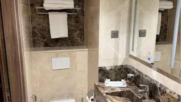 Un baño con tocador de mármol, inodoro, lavamanos y ducha.