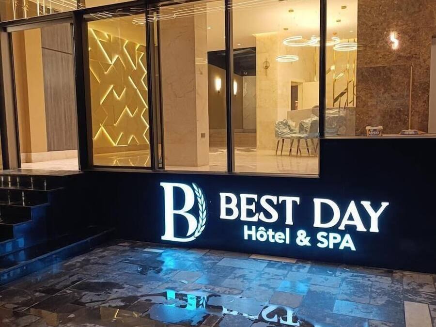 A hotel entrance with a modern design, featuring a glass facade and a sign that reads "Best Day Hotel & SPA".