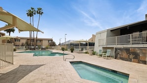 A pool area with two swimming pools, lounge chairs, and a covered seating area.