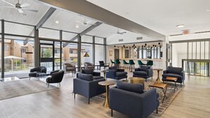 A spacious lounge area with modern seating, large windows, and ceiling fans.