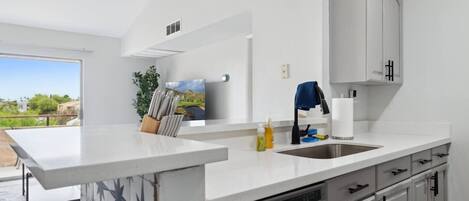 A modern kitchen with a large island, stainless steel appliances, and a view to the outdoors.