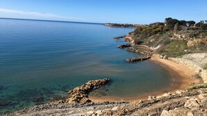 A coastal landscape with clear blue waters, rocky shores, and a distant shoreline with buildings. - ApartHotel Capo Rizzuto - Sea View Apartments 40mt from the Reserved Beach (Capo Rizzuto)