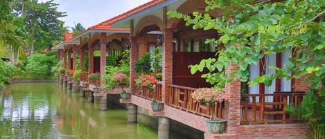 A row of traditional-style buildings with brick walls and tiled roofs, connected by a waterway.
