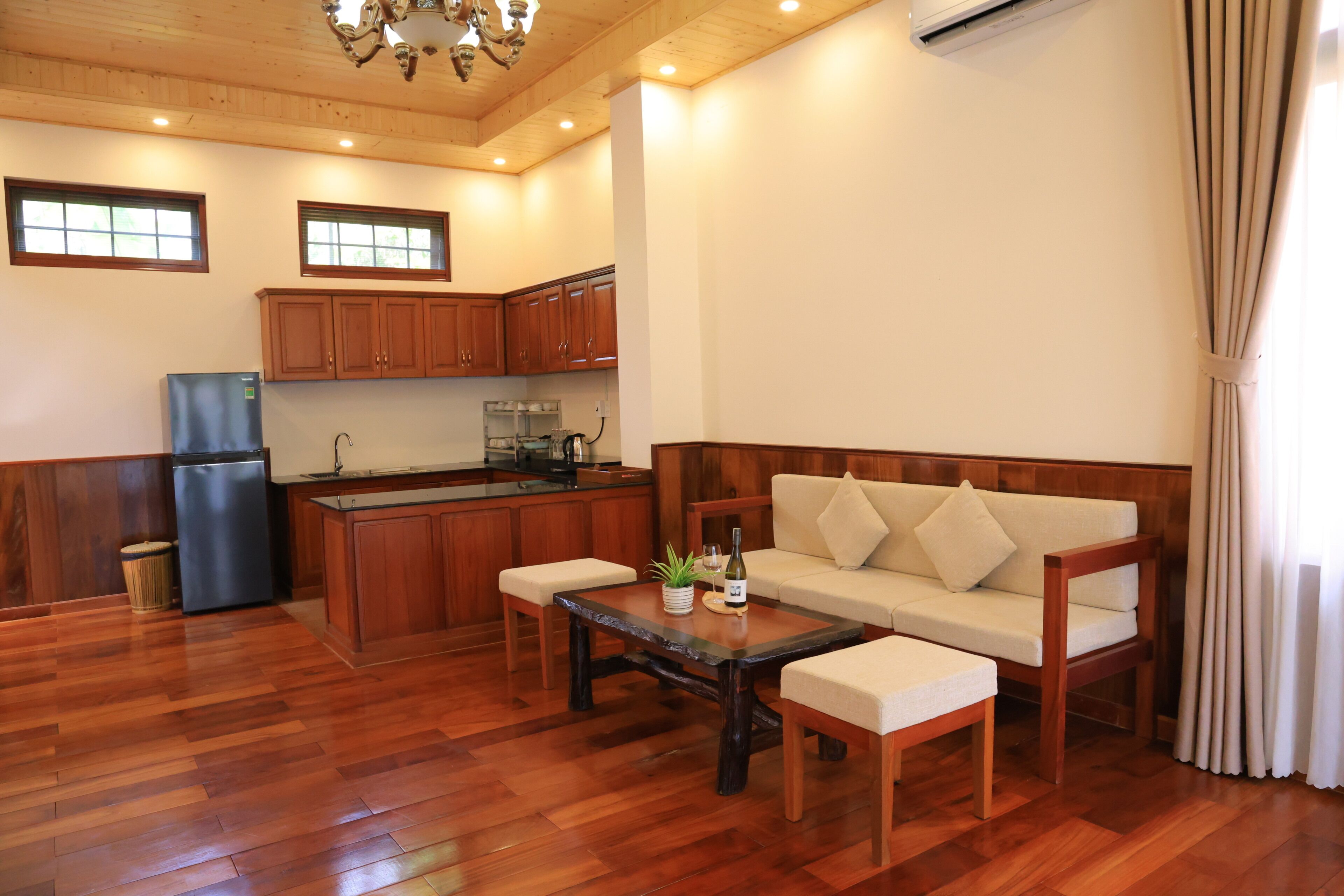 Un salón espacioso con piso de madera, un sofá, una mesa de centro y una cocina al fondo.
