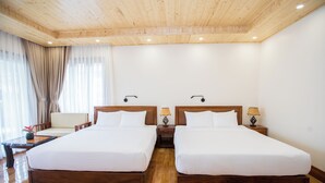 A hotel room with two beds, wooden flooring, a wooden ceiling, and a window with curtains. - Phi Yen Eco Resort (Can Tho)