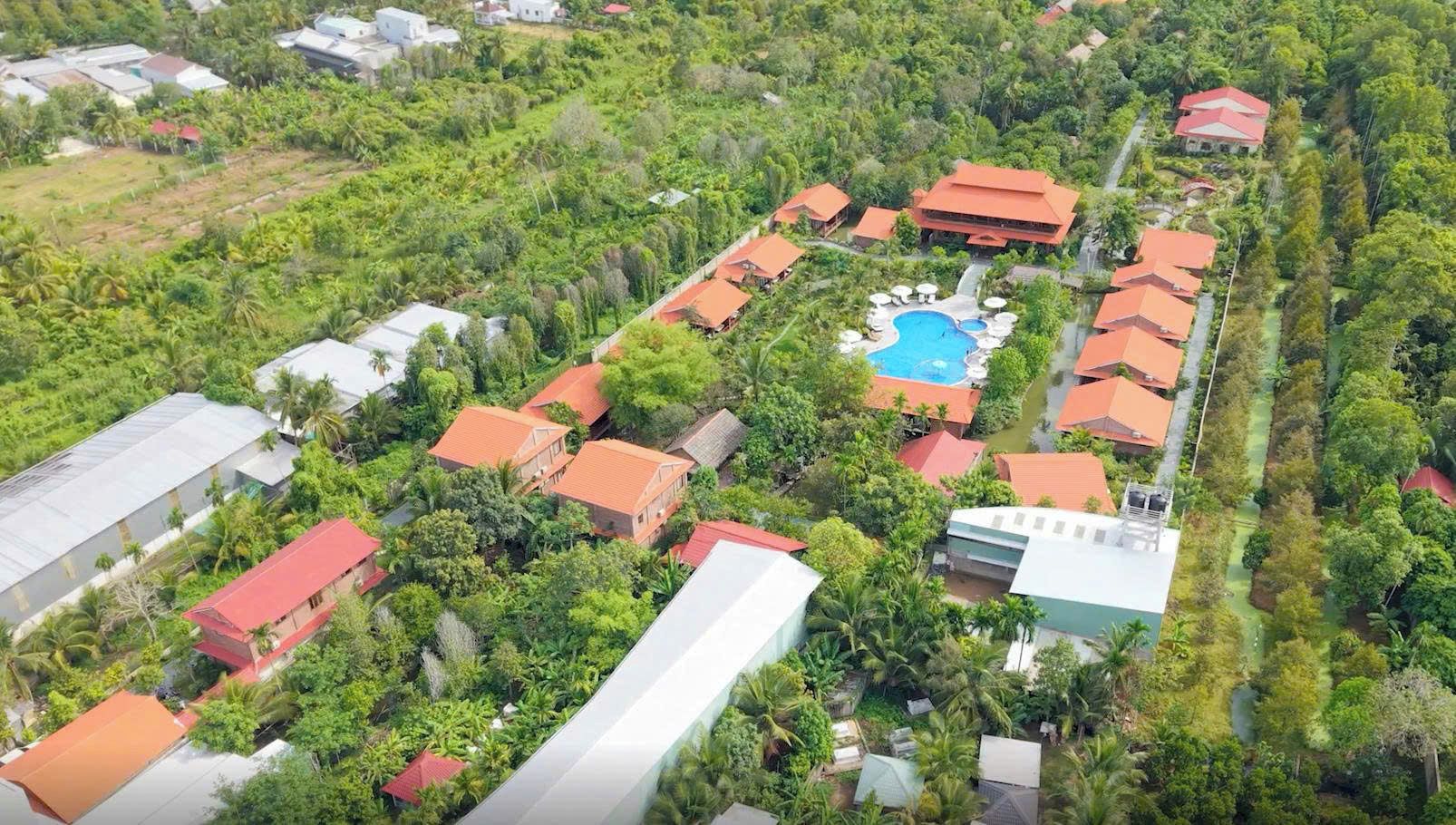 An aerial view of a resort with multiple buildings, a swimming pool, and lush greenery.