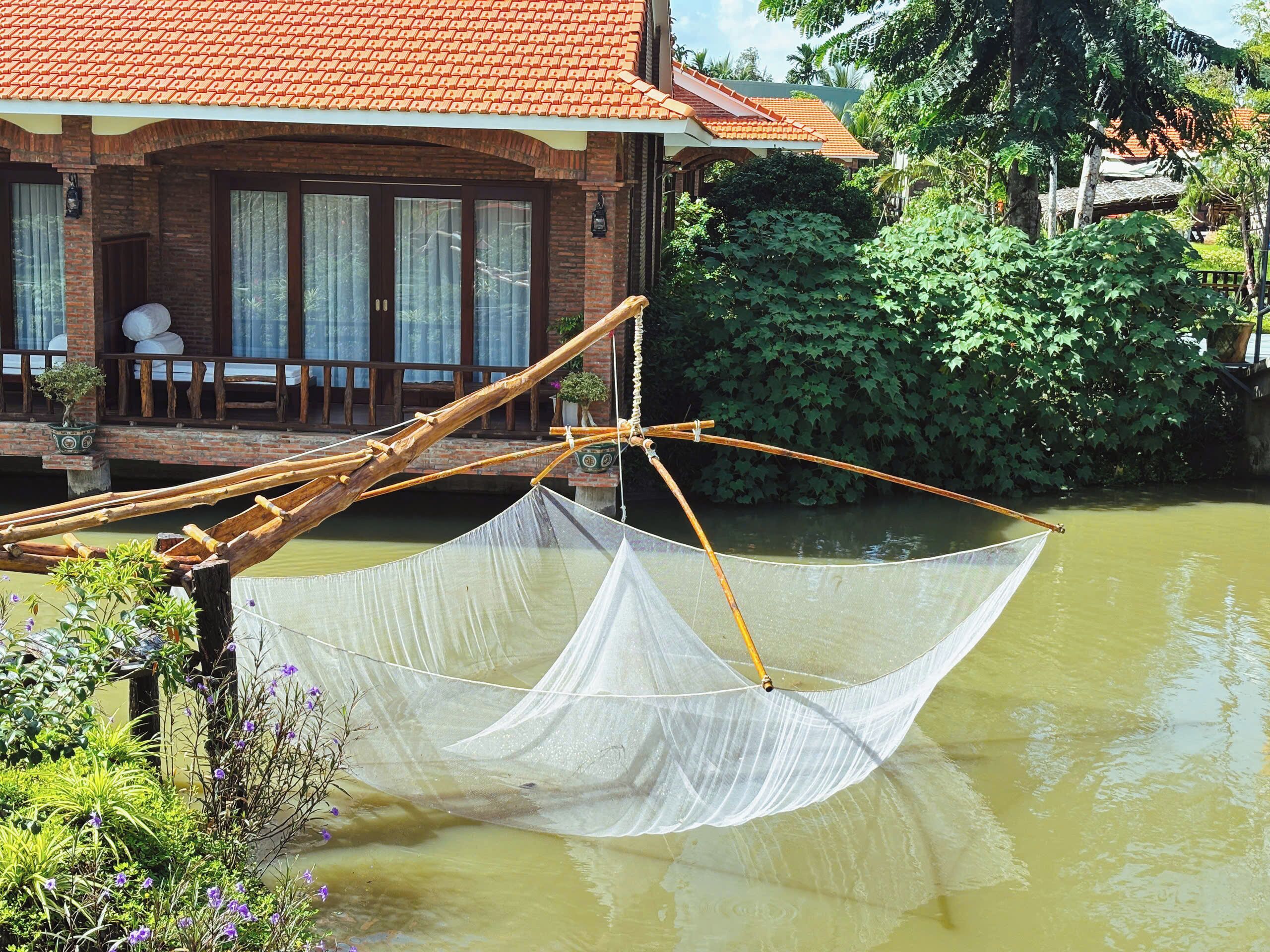 Una casa tradicional con techo de tejas, un porche de madera y un cuerpo de agua en primer plano.