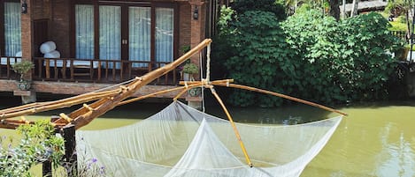 Una casa tradicional con techo de tejas, un porche de madera y un cuerpo de agua en primer plano.