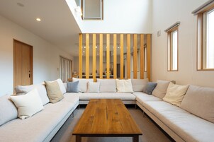 Una sala de estar moderna con un amplio sofá modular, una mesa de centro de madera y un separador de listones de madera.