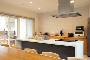 Una cocina moderna con encimera blanca, microondas integrado y un amplio ventanal con vistas a un balcón.