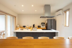 Una cocina moderna con una isla central, electrodomésticos integrados y una zona de comedor con sillas de madera.