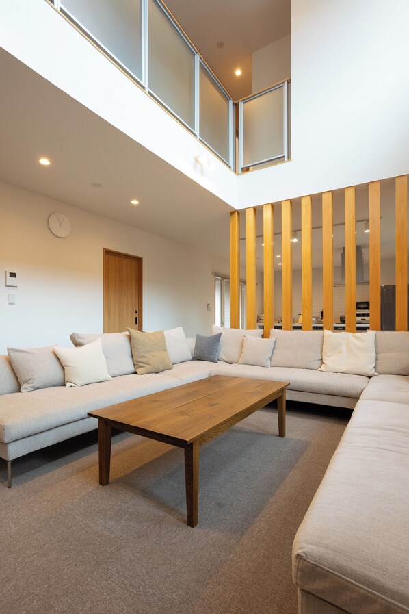 A modern living room with a sectional sofa, a wooden coffee table, and a kitchen in the background.