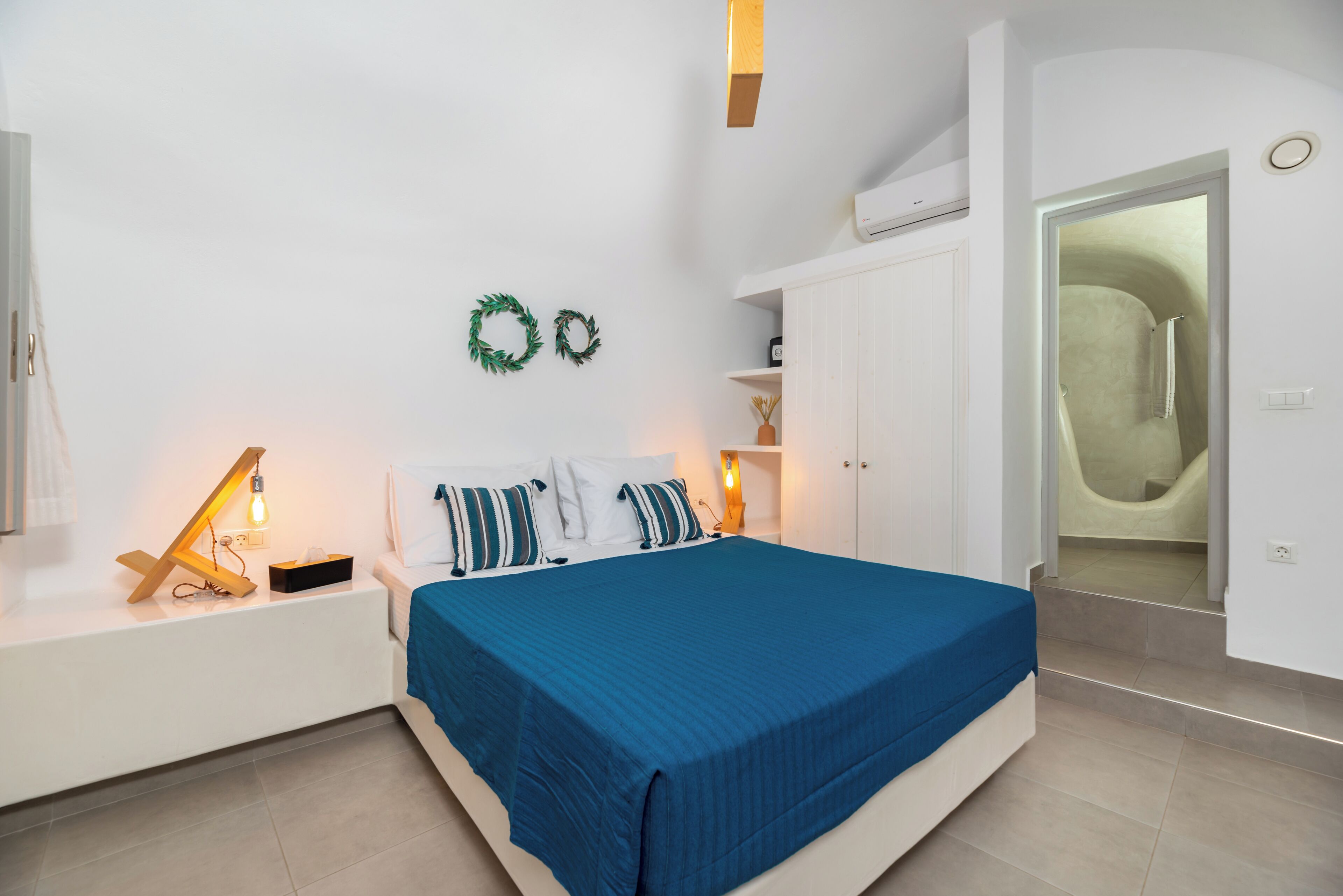 Un dormitorio con cama, mesitas de noche, lámpara de pared, armario y zona de ducha.