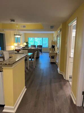 Una cocina amplia con comedor, piso de madera y ventanas grandes.
