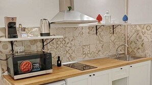 A compact kitchen with white cabinets, a wooden countertop, a built-in microwave, a coffee maker, and a small sink. - Very nice little apartment in the heart of the beautiful island of Ortigia (Siracusa)