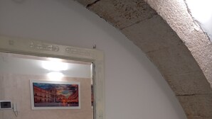 A bedroom with a bed, a colorful quilted sofa, a lamp, and a painting on the wall. - Very nice little apartment in the heart of the beautiful island of Ortigia (Siracusa)