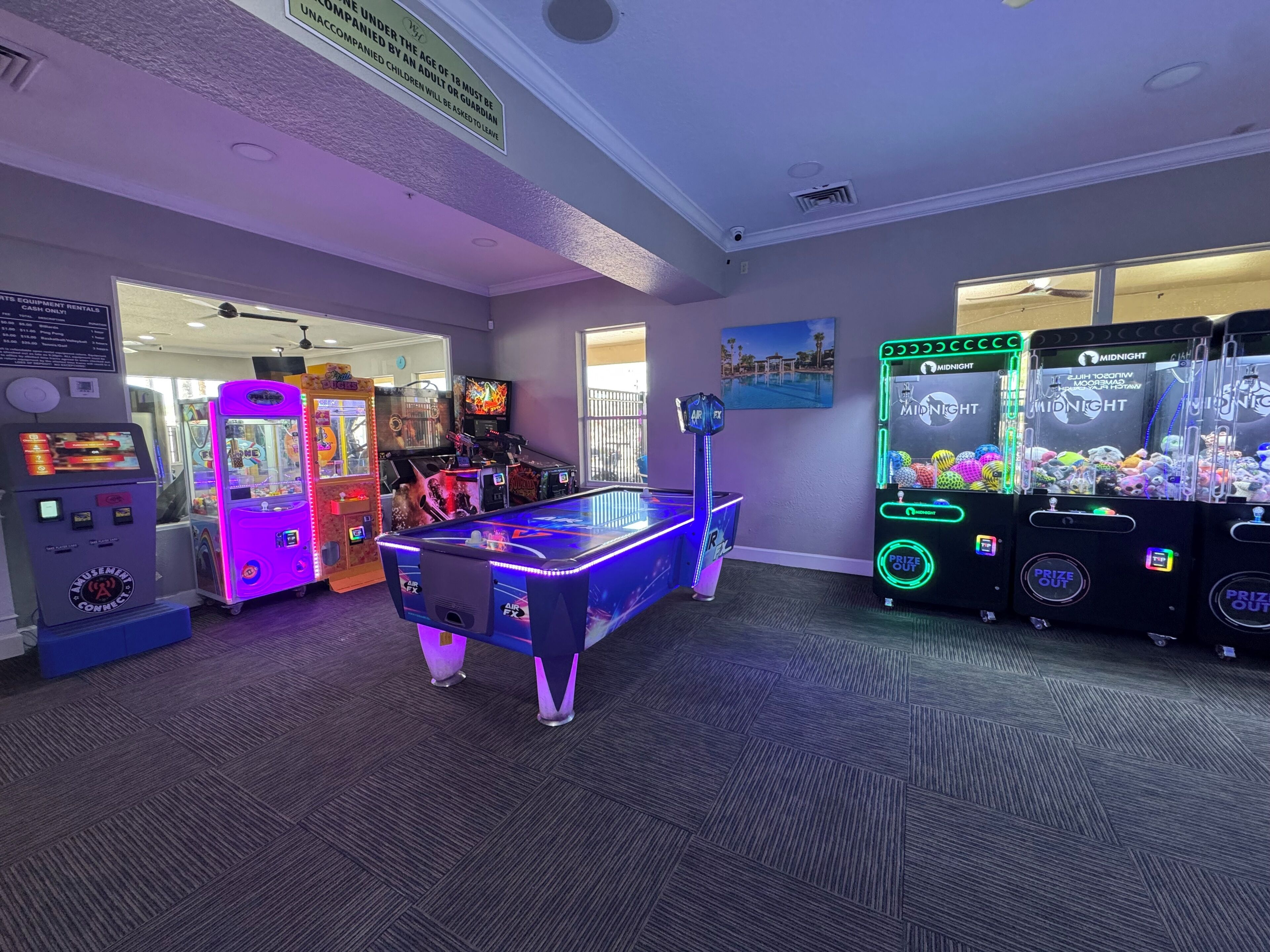 Eine Indoor-Spielhalle mit verschiedenen Spielautomaten, darunter Krabschere-Spiele und ein Billardtisch.