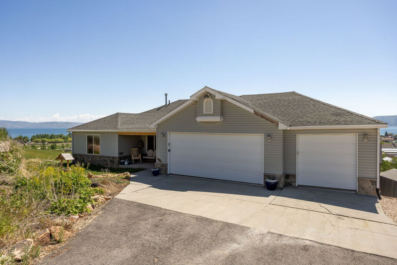 A single-story house with a garage, a covered porch, and a view of the ocean.