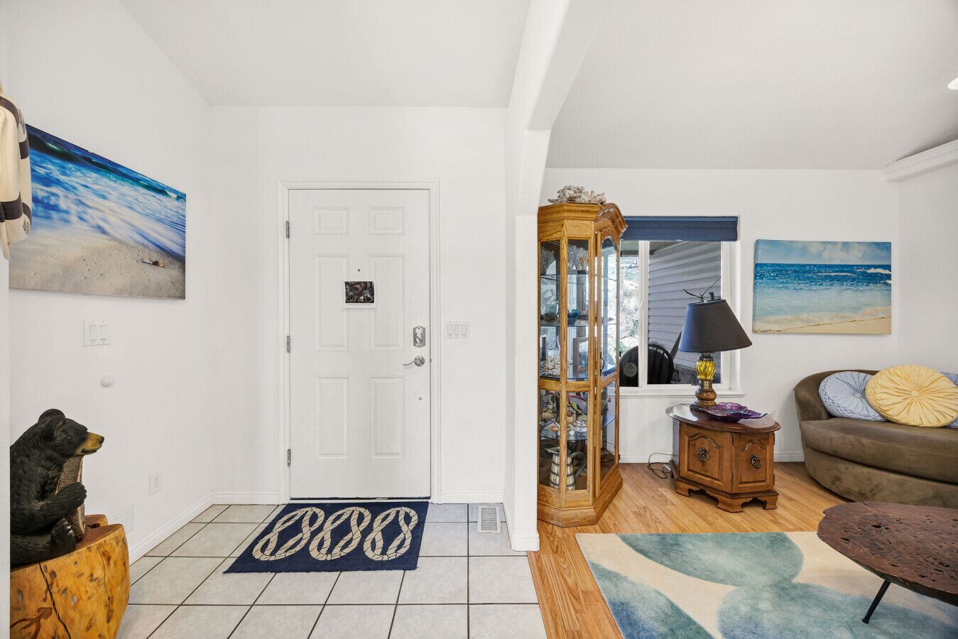 Un salón amplio con una puerta blanca, un mueble de madera, un sofá y una alfombra.
