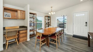 A spacious kitchen with a large wooden table, built-in shelves, and a view through the window. - Juuust Right - Gorgeous view, 5 mins from the lake (Garden City)