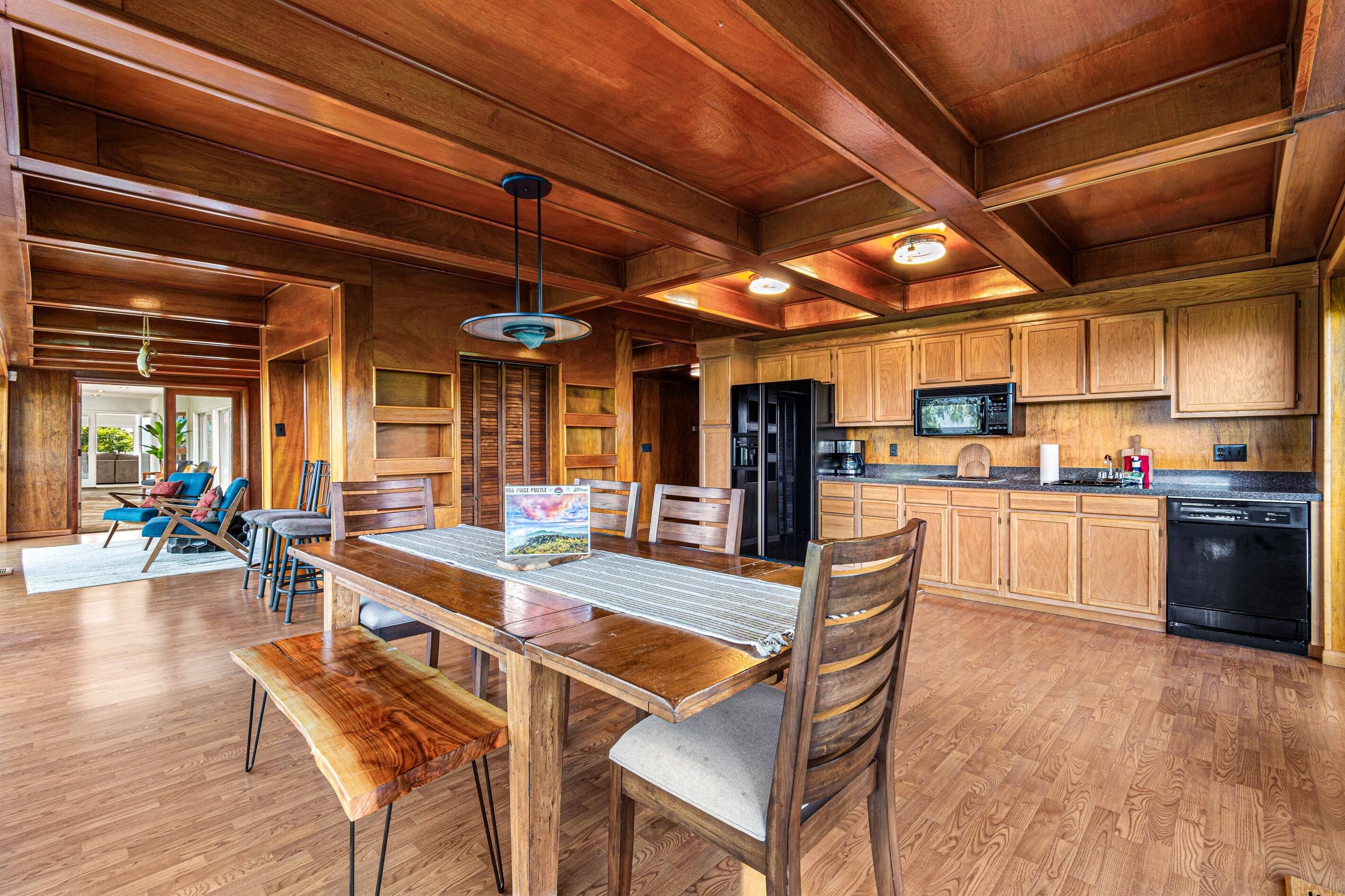 Une cuisine spacieuse avec des meubles de rangement en bois, une table à manger avec des chaises et un grand îlot central.