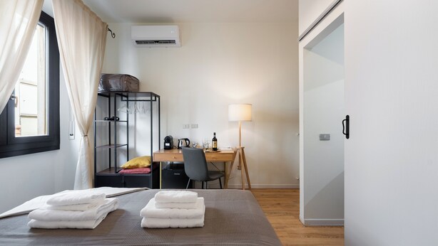 Ein Hotelzimmer mit Bett, Schreibtisch, Stuhl, Lampe und Kleiderschrank.