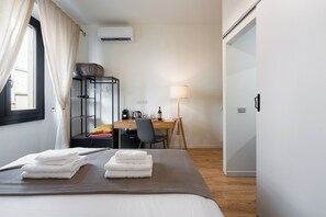 A hotel room with a bed, a desk, a chair, a lamp, and a wardrobe.